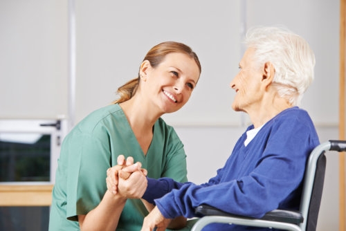 caregiver holding hands with senior women in a wheelchair